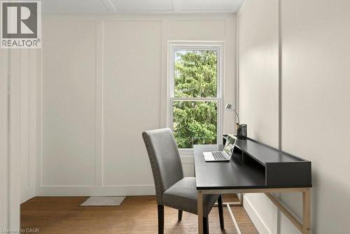 Room featuring light wood-finish flooring, a single window with white trim, and light-colored walls with board and batten detailing - 148 Dundurn Street N, Hamilton, ON 