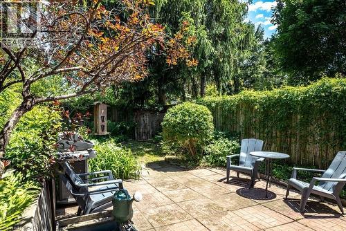 Expansive backyard with a paver patio area, mature trees, lush greenery, and a wood privacy fence - 148 Dundurn Street N, Hamilton, ON 