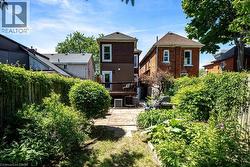 Expansive backyard featuring a wood fence with climbing greenery, mature landscaping, and a patio area - 