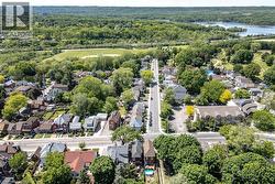 Aerial perspective showcasing a residential neighborhood with tree-lined streets, a distant body of water, and surrounding green spaces - 