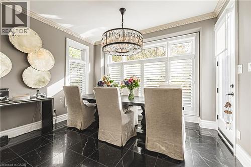 Formal dining space featuring dark stone tile flooring with white veining, crown molding, and a chandelier - 712 Highvalley Road, Ancaster, ON 