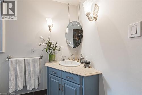 Bathroom vanity featuring a blue cabinet, integrated sink, and light-toned countertop - 712 Highvalley Road, Ancaster, ON 