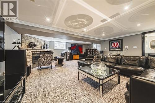Spacious recreation room featuring a stone-clad fireplace, recessed lighting, crown molding, a patterned carpet, and a built-in wall niche - 712 Highvalley Road, Ancaster, ON 