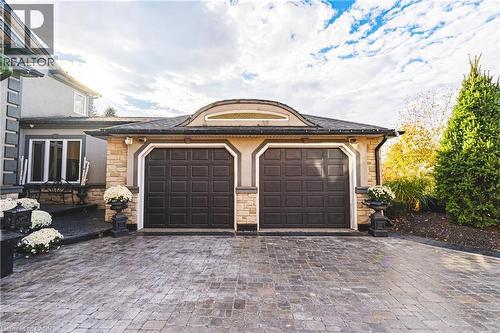 Two-car garage with arched detailing, paneled doors, and stone veneer accents - 712 Highvalley Road, Ancaster, ON 