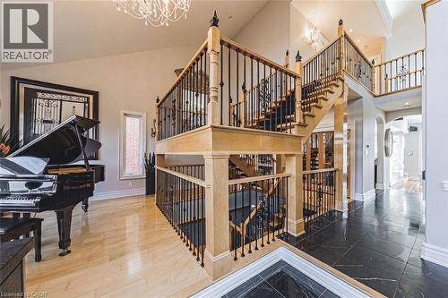 Grand foyer featuring a dual staircase with natural wood handrails and wrought iron balusters - 712 Highvalley Road, Ancaster, ON 