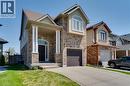 Two-story home with a brick and siding exterior, featuring a covered porch with white columns, an arched transom window above the dark front door, and a single-car garage with a brown door - 928 Dunblane Court, Kitchener, ON 