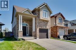 Two-story home with a brick and siding exterior, featuring a covered porch with white columns, an arched transom window above the dark front door, and a single-car garage with a brown door - 
