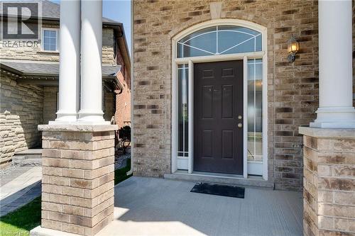 Brick facade entrance featuring a dark paneled door with sidelights, an arched transom window, and a concrete porch - 928 Dunblane Court, Kitchener, ON - Outdoor