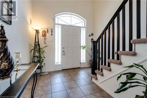 Entryway featuring a white door with an arched transom window, side lights, tile flooring, and a dark wood-finish staircase with carpeted treads - 928 Dunblane Court, Kitchener, ON - Indoor Photo Showing Other Room