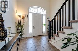 Entryway featuring a white door with an arched transom window, side lights, tile flooring, and a dark wood-finish staircase with carpeted treads - 