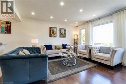 Spacious living area featuring expansive windows, recessed lighting, hardwood-finish flooring, and a neutral color palette - 