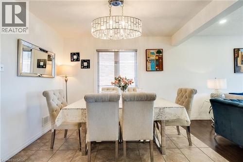 Dining area featuring a prominent chandelier with crystal accents, tile flooring, and a large window with privacy blinds - 928 Dunblane Court, Kitchener, ON - Indoor Photo Showing Dining Room