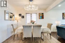 Dining area featuring a prominent chandelier with crystal accents, tile flooring, and a large window with privacy blinds - 