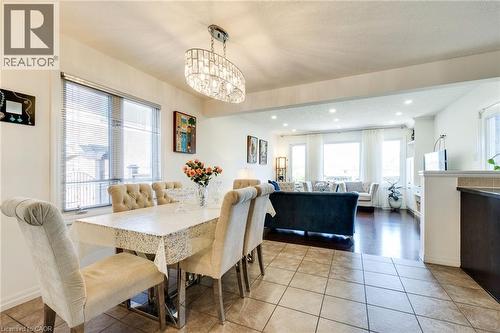 Open concept dining area featuring a contemporary crystal chandelier, tile flooring, and ample natural light - 928 Dunblane Court, Kitchener, ON - Indoor Photo Showing Dining Room