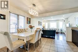 Open concept dining area featuring a contemporary crystal chandelier, tile flooring, and ample natural light - 