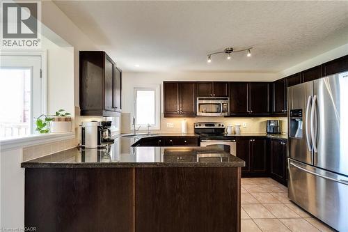 Kitchen featuring dark wood-finish cabinetry, stainless steel appliances, granite-style countertops, and tile flooring - 928 Dunblane Court, Kitchener, ON - Indoor Photo Showing Kitchen With Double Sink