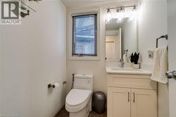 Bathroom featuring a single vanity with a white countertop and base cabinetry, brushed nickel hardware, an integrated sink, and an overhead vanity light fixture - 