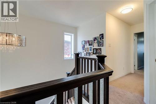 Upper-level landing featuring dark wood newel posts and railings, a contemporary chandelier, and recessed lighting - 928 Dunblane Court, Kitchener, ON - Indoor