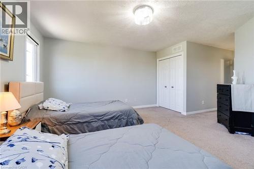 Carpeted room featuring a double bi-fold door closet, a window with trim, and a ceiling-mounted light fixture - 928 Dunblane Court, Kitchener, ON - Indoor Photo Showing Bedroom