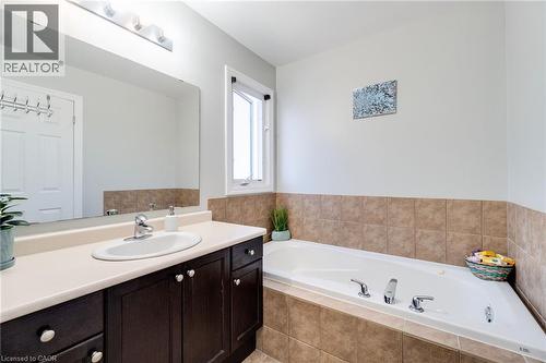 Bathroom with a built-in jetted tub, a single vanity with a white oval sink, and a large wall-mounted mirror - 928 Dunblane Court, Kitchener, ON - Indoor Photo Showing Bathroom
