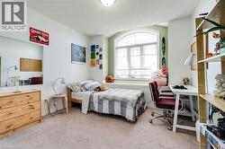 Bright room featuring a large arched window with a window seat, light-toned carpet, and neutral wall tones - 
