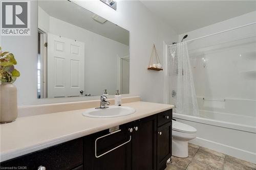 Bathroom featuring a vanity with a dark wood-finish cabinet and light-toned countertop, an undermount sink with a chrome faucet, a large wall-mounted mirror, and a white bathtub with an integrated sho - 928 Dunblane Court, Kitchener, ON - Indoor Photo Showing Bathroom