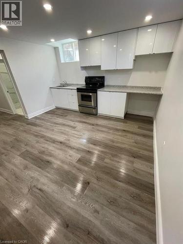 Modern kitchen space featuring glossy white cabinetry, stainless steel oven, and light-toned wood-finish flooring - 928 Dunblane Court, Kitchener, ON - Indoor Photo Showing Kitchen
