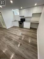 Modern kitchen space featuring glossy white cabinetry, stainless steel oven, and light-toned wood-finish flooring - 