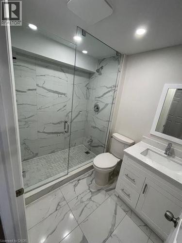 Modern bathroom featuring a frameless glass shower enclosure, white marble-look tile flooring, and a coordinating vanity with an integrated sink - 928 Dunblane Court, Kitchener, ON - Indoor Photo Showing Bathroom