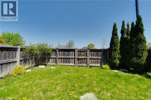 Expansive grassy area featuring mature cedar trees, established perimeter fencing, and natural stone accents - 928 Dunblane Court, Kitchener, ON - Outdoor