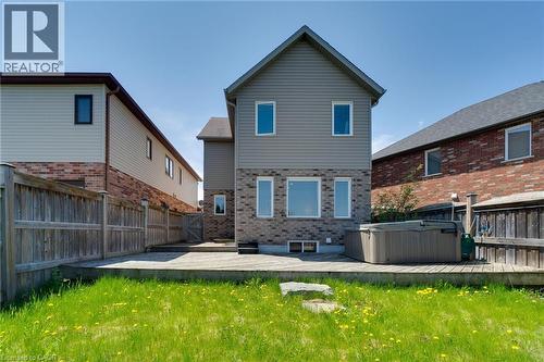 Rear exterior featuring a spacious wooden deck with an integrated hot tub, a manicured lawn, and a full privacy fence - 928 Dunblane Court, Kitchener, ON - Outdoor