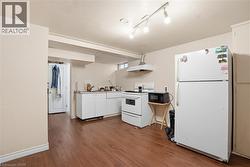 Kitchen area featuring wood-finish flooring, white cabinetry, track lighting, and a window - 