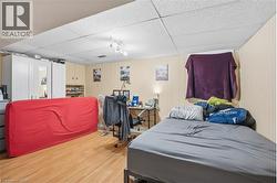 Versatile room featuring wood-finish flooring, drop ceiling with recessed lighting, and light-toned wall paneling - 