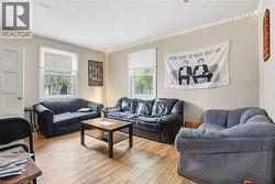 Living area featuring wood-finish flooring, light-colored walls, and multiple windows with blinds - 