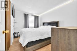 Bedroom featuring wood-finish flooring and a window with blinds - 