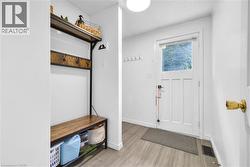 Entryway featuring wood-finish flooring and a built-in storage bench with coat hooks - 