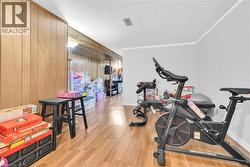 Open concept room featuring wood-finish flooring, light grey painted walls, and wood paneling - 