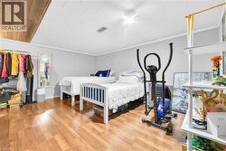 Spacious room featuring wood-finish flooring, light gray walls, and a white paneled ceiling - 