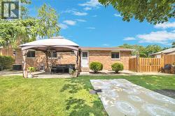 Expansive backyard with a manicured lawn, brick exterior, and a paved patio area - 