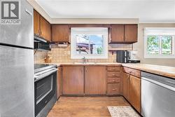 Kitchen featuring wood-finish cabinetry, stainless steel appliances, and a double basin sink - 