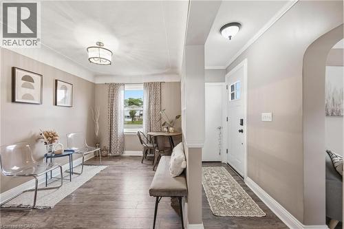 Inviting entryway featuring wood-finish flooring extending into the main living areas, a white entry door, and a decorative overhead light fixture - 481 Upper Gage Avenue, Hamilton, ON - Indoor