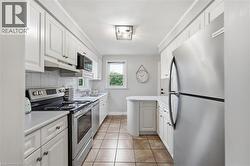 Kitchen featuring white cabinetry, stainless steel appliances, a white tile backsplash, and a curved countertop extension - 