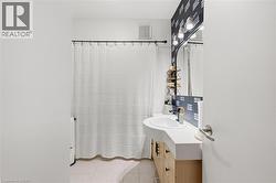 Bathroom featuring a vanity with an integrated sink, three-light fixture, and patterned accent wall - 