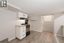 Kitchen area featuring a freestanding black and stainless steel range, range hood, white upper and lower cabinetry with dark hardware, a light-toned countertop, and private entrance - 