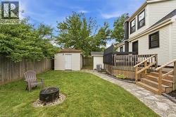 Expansive backyard featuring a wood privacy fence, stone pathway, and a multi-level wooden deck with steps - 