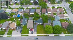 Aerial perspective highlighting a residential neighborhood with diverse architectural styles, mature trees, and paved roadways - 