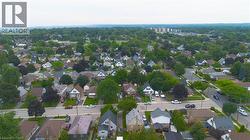 Aerial perspective highlighting a residential neighborhood with diverse architectural styles, mature trees, and paved roadways - 