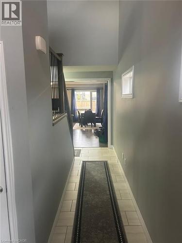 Hallway featuring light-toned rectangular floor tiles, neutral wall paint, and white baseboards - 766 Freeport Street, London, ON 