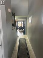Hallway featuring light-toned rectangular floor tiles, neutral wall paint, and white baseboards - 