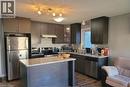 Kitchen featuring dark wood-finish cabinetry, light speckled countertops, stainless steel appliances, and wood-finish flooring - 766 Freeport Street, London, ON 